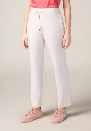 Pantalons de jogging rose clair en tissu doux et lisse avec une taille à cordon et des broderies sur les côtés. Associés à des baskets rose clair.