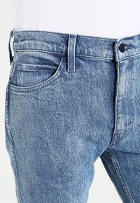 Ljusblå denimjeans med rak skärning, med en femfickdesign, synlig stickning och en knapp- och dragkedjestängning i midjan.