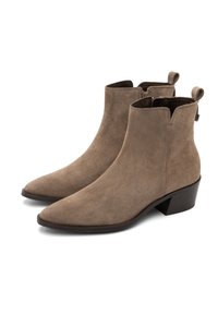 Un paio di stivaletti alla caviglia in suede taupe con cerniere laterali, punte appuntite, linguette per infilare e tacco basso a blocco su sfondo bianco.