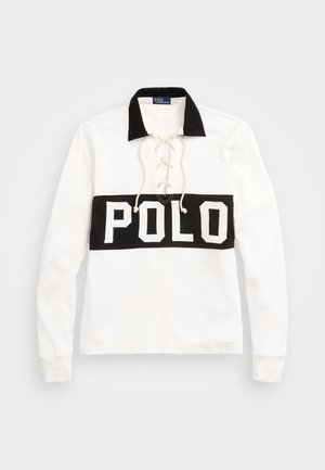 La polo shirt bianca a maniche lunghe presenta un colletto nero, un design frontale con lacci e una fascia orizzontale nera con la scritta "POLO" stampata in bianco.