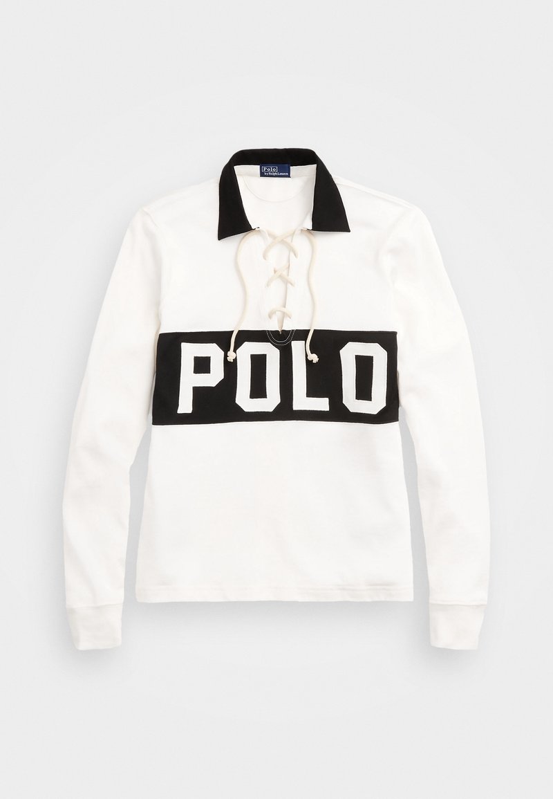 La camisa polo de manga larga blanca presenta un collar negro, un diseño frontal con cordones y una banda horizontal negra con "POLO" impreso en blanco.
