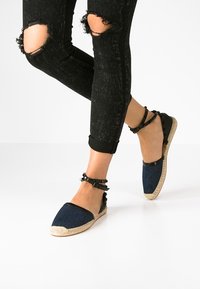 Denim espadriller med svarta ankelremmar; vävd jutesula; blå ovandel; rund tå; strukturerad tyg; avslappnad design; platt profil.