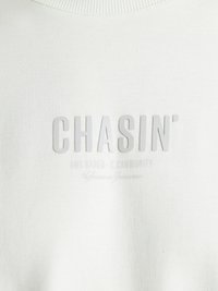 Hanorac alb cu guler rotund texturat, având un imprimeu proeminent  "CHASIN'" și un text subtil dedesubt într-o nuanță mai deschisă.