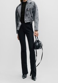 Jeansjacka i ljusgrått, figursydd svart topp, högmidjade svarta byxor, svarta spetsiga stövlar, liten svart texturerad väska med remmar.