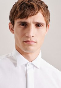 Camicia bianca con colletto classico, realizzata in tessuto morbido e dalla vestibilità su misura. Linee pulite e design minimalista.