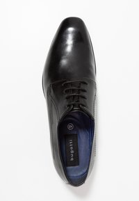 Chaussure en cuir noir avec une finition lisse, bout pointu et un design à lacets. L'intérieur présente une doublure bleue et un détail de marque. Taille 42.