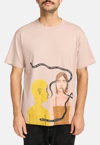 Light pink cotton t-shirt featuring a graphic of a yellow figure and a woman, with black text lines intertwined. Loose-fit short sleeves.