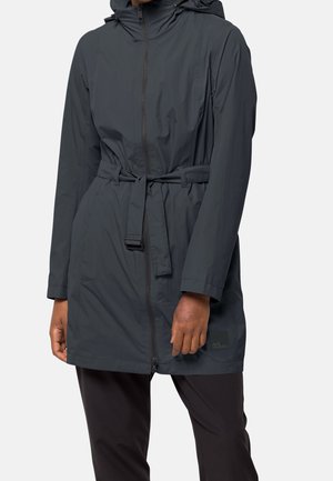 Abrigo de lluvia negro largo con capucha y cinturón en la cintura, llevado sobre pantalones negros, mostrado desde el cuello hasta la mitad del muslo en una persona de pie.