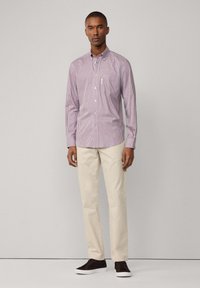 Camicia a quadretti rossi e bianchi con colletto button-down, abbinata a chinos beige e sneakers marrone scuro. Tessuto morbido con vestibilità classica.