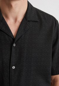 Zwart shirt met korte mouwen, een gestructureerd patroon, knoopsluiting, ingesneden kraag en een gladde stofafwerking.