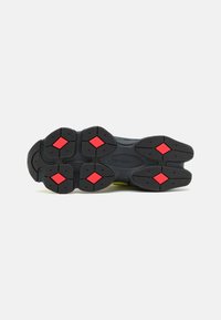 Black shoe sole with rubber material, featuring red diamond accents on the tread pattern. Solid, rounded shape with pronounced cushioning elements.