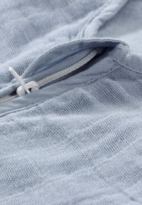 Light blue fabric with a textured finish and visible weaving pattern; features a white zipper with a pull tab.