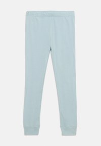Leggings en coton bleu clair avec une taille élastique et une coupe ajustée ; poignets aux chevilles avec un tissu lisse et légèrement texturé.
