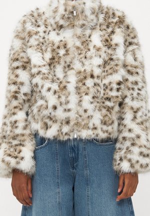 Chaqueta de pelo sintético con estampado de leopardo y cremallera, usada con vaqueros azules de talle alto, mostrada desde los hombros hasta las caderas.