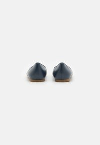 Scarpe flat navy con tomaia in pelle liscia, design a punta e suole in gomma marrone. Stile minimalista senza decorazioni.