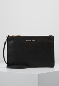Sort læder clutch taske med en pebret tekstur, guld hardware, lynlåslukning og håndledsrem. Guld "MICHAEL KORS" logo på fronten.