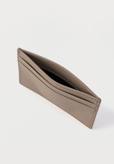 Λεπτός δερμάτινος θήκη καρτών σε απόχρωση ταουπ με τρεις θήκες για κάρτες και κεντρικό διαμέρισμα, εμφανιζόμενη ελαφρώς ανοιχτή πάνω σε λευκή επιφάνεια.