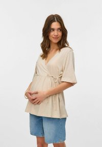 Kastes krāsas apņemjoša blūze ar īsām piedurknēm, savilkta zem krūtīm, mīksta tekstūra, komplektā ar džinsu šortiem. Dizainā iekļauts jostas akcenta saites elements.