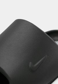 Μαύρο σανδάλι με λουρί, με ομαλή, ματ επιφάνεια και ανάγλυφο λογότυπο Nike στο πλάι. Διαθέτει ανοιχτή μύτη και σχεδιασμό χωρίς πίσω μέρος.