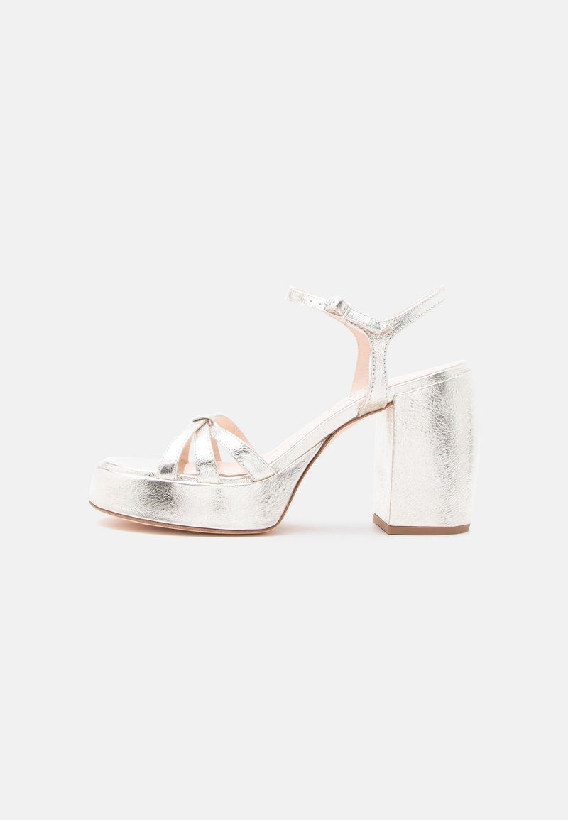Ασημένιο μεταλλικό πλατφόρμα σανδάλι με τακούνι μπλοκ, λουράκι στον αστράγαλο και ανοιχτή μύτη με λουριά που διασταυρώνονται.