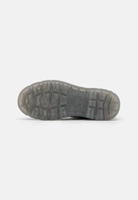 Suela de zapato atlético negra, texturizada con un patrón de relieve multidireccional. Material de goma translúcido con un diseño grueso y duradero.