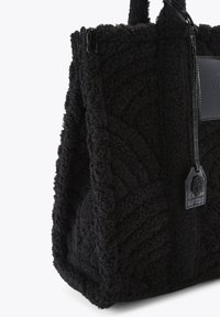 Zwarte getextureerde tote bag met een zachte, donzige oppervlakte. Beschikt over een handvat van gepatenteerd leer en een gestikt logo-label. Vierkante vorm met een brede opening.