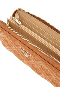 Portafoglio marrone chiaro con design a quilted, zipper dorato e diversi scomparti. L'interno presenta una fodera beige chiaro e slot per carte.