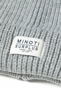Sivi rebrasti pleteni tekstil s tkanim etiketom koji prikazuje "MINOTI SURPLUS", ističući čist dizajn i meku teksturu.