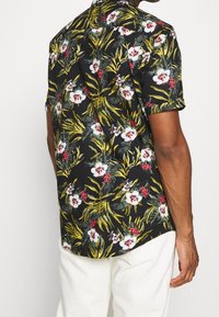 Lyhythihainen paita, jossa musta tausta ja värikkäitä kukka- ja lehtikuvioita. Kevyt kangas; rento malli, jossa taitetut hihat.