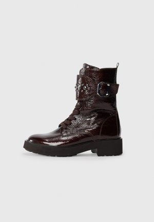 Bordeauxfarbene, patentierte Leder-Stiefeletten mit runder Zehe, Schnürung an der Vorderseite, Riemen- und Schnallendetails sowie einer strukturierten Oberfläche des Obermaterials.