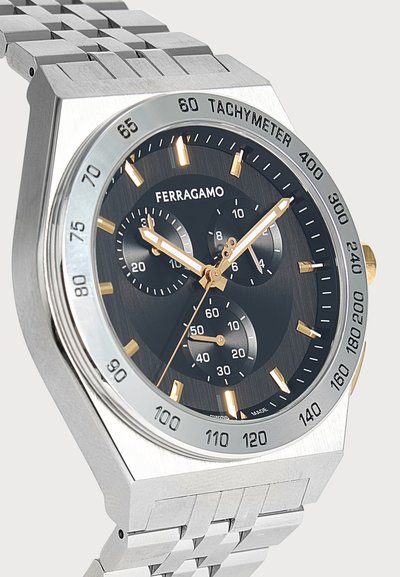 Ασημένιο ρολόι χειρός Ferragamo με ταχύμετρο, μαύρο καντράν, χρυσούς δείκτες και τρεις υποκαντράν σε ασημένιο μεταλλικό μπρασελέ.
