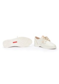 Zapatos de cordones de un beige claro, hechos de cuero suave, con una lengüeta acolchada, suela de goma texturizada y un diseño minimalista.