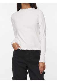 Vit ribbad långärmad topp med en scallop-krage och fåll, med en figurnära design och mjuk textur. Kombinerad med mörka byxor.