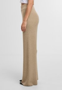 Pletená béžová sukně s vysokým pasem, s texturovaným vzorem, splývavým designem a dlouhým střihem. Hladký povrch na lemu.