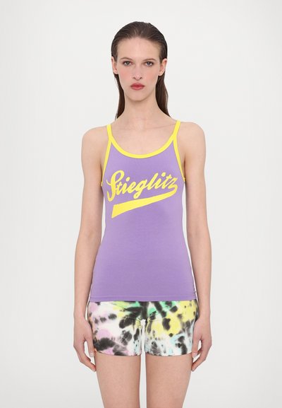 Lilla tanktop med gul trim og teksten "Stieglitz", parret med flerfarvede tie-dye shorts. Blødt bomuldsstof, tætsiddende design.