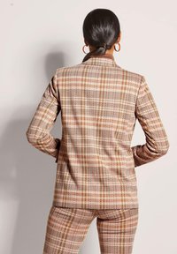 Geruit colbert in tinten van roze en bruin, met een notch lapel, gestructureerde pasvorm en een textuur met een visgraatpatroon.