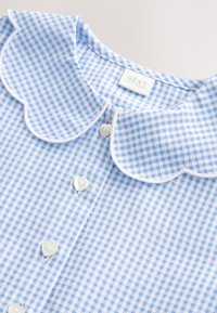 Robe en vichy bleu et blanc avec col festonné et boutons en forme de cœur, l'étiquette indique "NEXT Made in Sri Lanka."