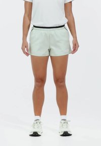 Pantalones cortos deportivos de color verde claro con una cinturilla elástica negra y bolsillos laterales, fabricados con un tejido suave y transpirable.