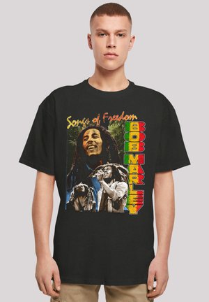 Schwarz shirt mit bunten Grafiken von Bob Marley und dem Text "Songs of Freedom." Die Bilder zeigen Marley beim Singen und Gitarre spielen.