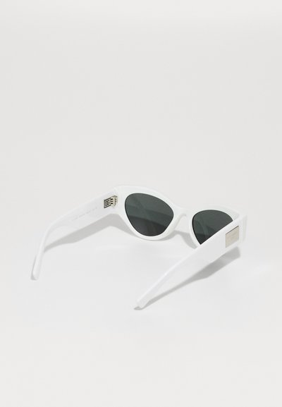 Bílé plastové sluneční brýle s ostrým kočičím tvarem. Tmavě zabarvené čočky a kovové logo na stranách. Elegantní a moderní design.