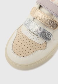 Sneakers med lyst kremfarget skinn og beige semsket skinn med perforeringer, pyntet med metalliske gull-, sølv- og roségullstropper.