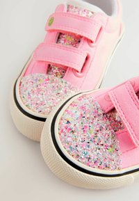 Zapatillas de lona rosas con correas de velcro, que cuentan con una puntera brillante en rosa, plateado y purpurina multicolor, y una suela de goma texturizada.