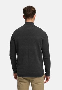 Dunkelgrauer Pullover mit Stehkragen, der strukturierte Streifen und gerippte Bündchen aufweist. Er besteht aus Strickmaterial und hat eine taillierte Passform.