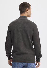 Pull en maille gris foncé avec un col, texture côtelée et manches longues, vu de dos. Porté avec un jean bleu.