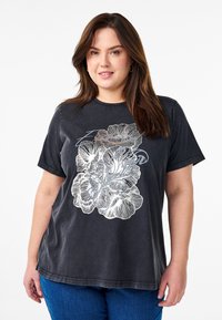 Camiseta de algodón negra con mangas cortas y un corte holgado, que presenta un gran diseño floral plateado en la parte delantera.