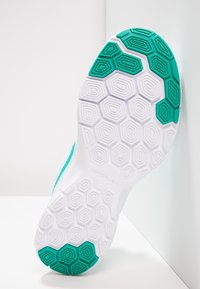 Nike-kenkäpohja, jossa on valkoinen pohja ja vihreä kuusikulmainen kuvio. Sisältää teksturoituja pitoelementtejä pidon parantamiseksi ja sujuvan siirtymäalueen.