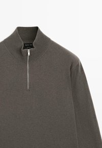 Maglione in lana marrone con zip a metà e colletto a coste, con dettagli sulla parte superiore anteriore e sul manica sinistra.