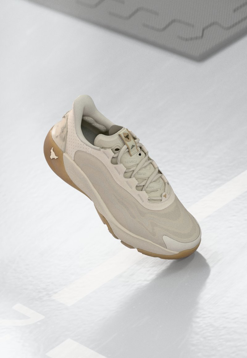 Sneakers con una toma superiore in tessuto beige chiaro, design tono su tono, chiusura con lacci e suola in gomma marrone. Branding sottile sulla linguetta e sul lato.