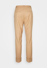 Pantalon beige sur mesure, poches avant, ourlet retroussé, texture lisse, deux poches arrière et passants pour ceinture.