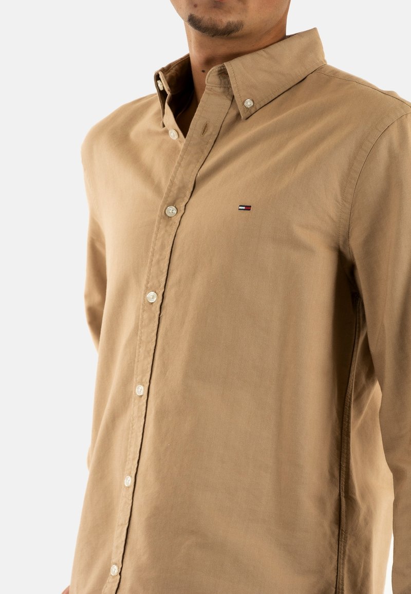 Lichtbeige katoenen overhemd met een kraag en knoopsluiting. Beschikt over een klein logo op de borst en knopen aan de voorkant. Valenciaanse textuur.